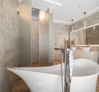 A bathroom in a family house with a freestanding bathtub and shower, floor with wooden decor.