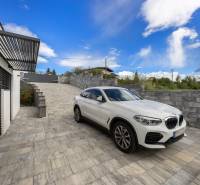 A family house in Dolný Kalník with a parking area and outdoor seating on a paved terrace.