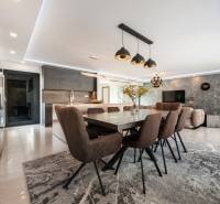 Interior of a family house with a dining room, kitchen, table, and comfortable chairs.