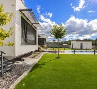 A family house in Dolný Kalník with a lawn, a swimming pool, and modern architecture in the garden.