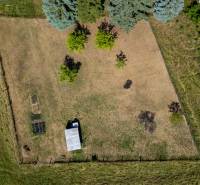 Aerial view of a residential plot in Banská Belá with grassy area and trees.