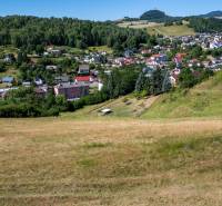 Greenery and houses in Banská Belá on residential plots surrounded by hills and forests.