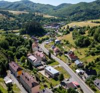 An aerial view of Banská Belá surrounded by hills and residential lands.