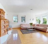 Living room in a family house with a tiled stove, sofa, and wooden decor flooring.