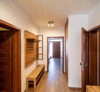 A hallway in a family house with wooden decor on the floor and furniture.
