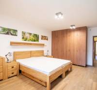 A bedroom in a family house with a bed, wardrobes, and a floor with a wooden decor.