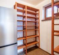 Fridge and wooden shelves in the pantry of a family house with a wooden decor floor.