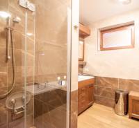 A bathroom in a family house with ceramic tiles and a shower enclosure, floor with a wooden decor.