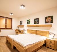 Bedroom in a family house with a wood-decor floor, paintings, and desks.