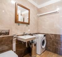 A bathroom in a family house with a washing machine, a sink, and a floor with a wooden decor.