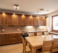 A kitchen in a family house with a wooden decor, equipped with wooden furniture and a dining table.