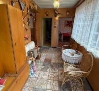 Interior of a family house with a tiled floor, wooden paneling, wicker furniture, and decorations.