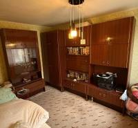 A room in a family house with furniture, a bed, and patterned wallpaper on the walls.
