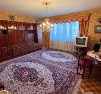 Living room in a family house with a carpet, an older television, and an elegant chandelier.