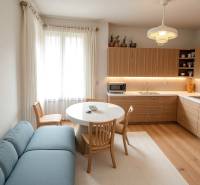 Bright kitchen in a family house with wooden decor, blue sofa, and round table.