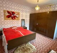 Bedroom in a family house with carpet, patterned wallpaper, and a large wardrobe.