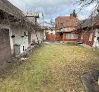 A family house in Babiná with a yard and a garage, visible older buildings and a fence.