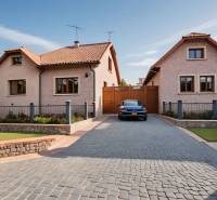 A family house in Babiná with a car on a paved yard and a garden.