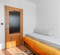 A simple room in a 4-room apartment with a bed and a wooden decor floor.