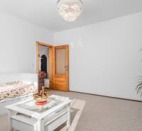 A bright room with floral bedding, a table, and a chandelier in a 4-room apartment.