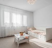 A bright room in a 4-room apartment with a sofa, a table, and curtains on the window.