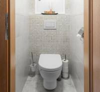A toilet in a 4-room apartment with tiled walls and storage space.