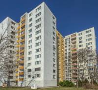 A high-rise building with balconies on Ševčenkova Street in Bratislava, Petržalka, surrounded by trees.