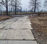 Area with a paved road and gate on Východná Street in Poprad, warehouses and halls.