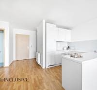 A kitchen in a 2-room apartment with white cabinets and a wooden decor floor.