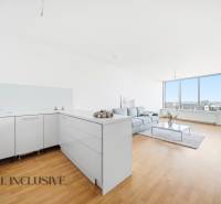 A bright kitchen with a living room, wood-patterned flooring, a sofa, large windows.