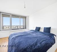 Bedroom in a 2-room apartment with a bed and a large window, floor with wooden decor.
