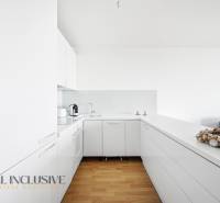 White kitchen in a 2-room apartment with wood-patterned flooring and appliances.