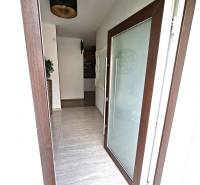 Entrance to a family house with large glass doors and a floor with a wooden decor.