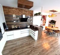 A kitchen in a family house with a wooden decor floor, a dining table, and decorative lights.