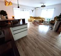 Living room in a family house with a wooden decor floor and a light-colored sofa.
