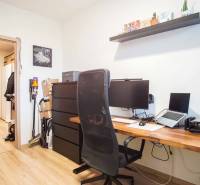 A workspace in a 3-room apartment with a wooden decor floor and a shelf above the desk.