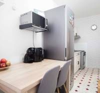 A kitchen in a 3-room apartment with a refrigerator, microwave, and kitchen table.