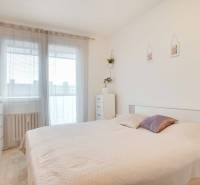 Bedroom in a 3-room apartment with a light-colored bed and dresser, decorated with a plant.