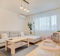 A bright living room with a sofa, children's toys, and a wooden decor floor in a 3-room apartment.