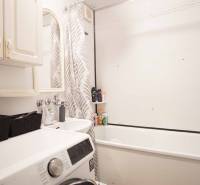 The bathroom in the 3-room apartment includes a bathtub, a washing machine, and storage spaces.