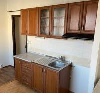A kitchen in a 3-room apartment with wooden cabinets and tiles, floor with wooden decor.