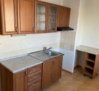 A kitchen with wooden cabinets and a sink in a 3-room apartment, flooring with a wooden decor.