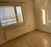 A room with a large window and a wooden decor floor in a 3-room apartment.