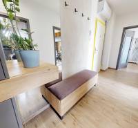 A hallway in a 3-room apartment with a bench, wooden decor flooring, and a plant on the table.
