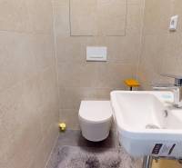 A compact bathroom with light tiles, a sink, and a toilet in a 3-room apartment.