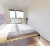 Bedroom in a 3-room apartment with a large window, bed, and floor with wood decor.