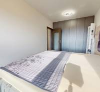 Bedroom with a large bed, built-in wardrobe, and wood-patterned flooring in a 3-room apartment.
