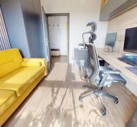 A study in a three-room apartment with a wooden decor floor and a yellow sofa.