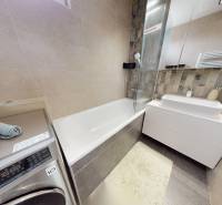 Bathroom in a 3-room apartment with a shower, washing machine, and a sink on a cabinet.