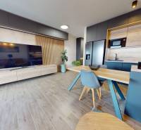 Living room in a three-room apartment with a wood-patterned floor and a kitchen.